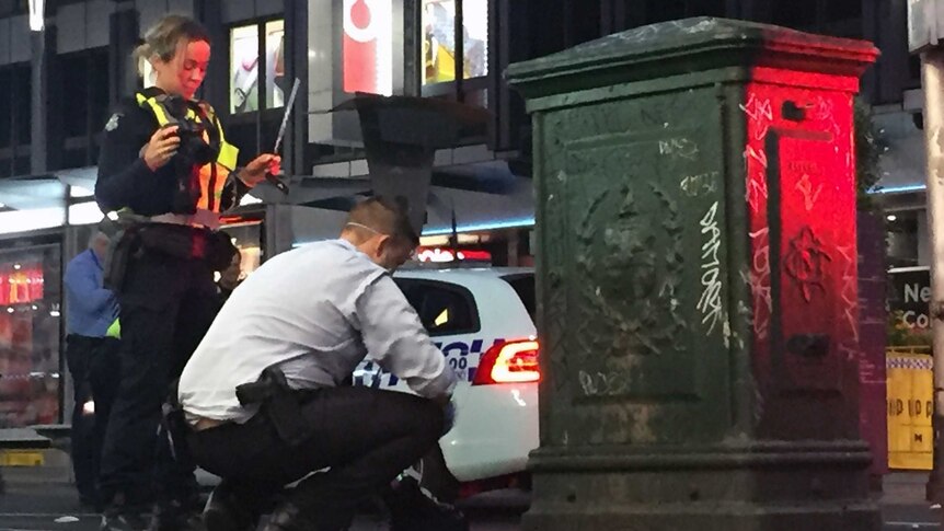 Police collect evidence at Elizabeth Street in Melbourne after two people were stabbed