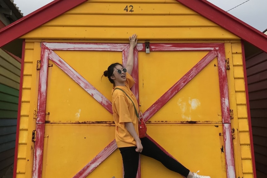 A woman in an orange shirt poses in front of an orange barn.