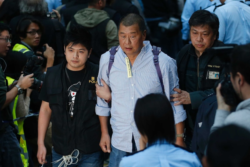 Medialny potentat Jimmy Lai, w środku, jest prowadzony przez funkcjonariuszy policji.