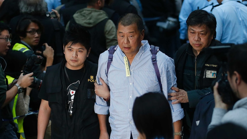 Media magnate Jimmy Lai, center, is taken away by police officers.