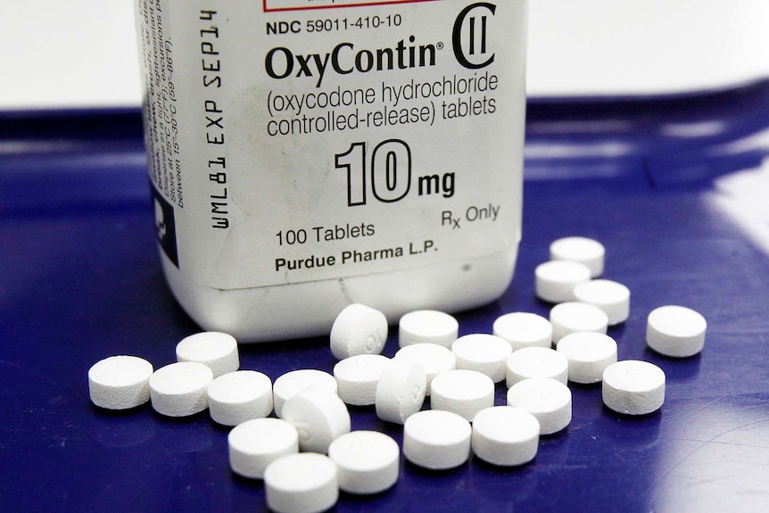 An OxyContin bottle with tablets surrounding it.