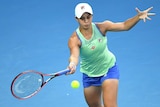A tennis player moves forward to hit a forehand, with her other hand held high off to her side.