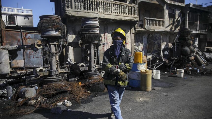 A firefighter stands next to the remains of a charred black truck that was carrying gasoline and exploded