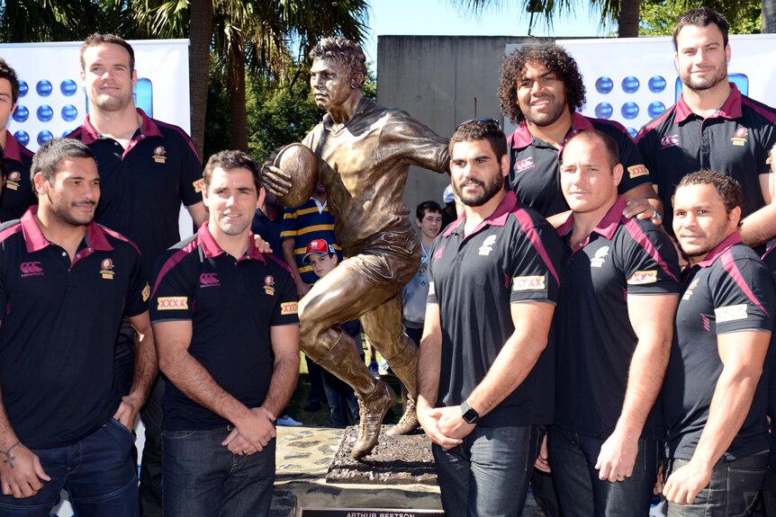 Queensland State of Origin team stand next to the statue of 'Artie' Beetson after it's unveiling.