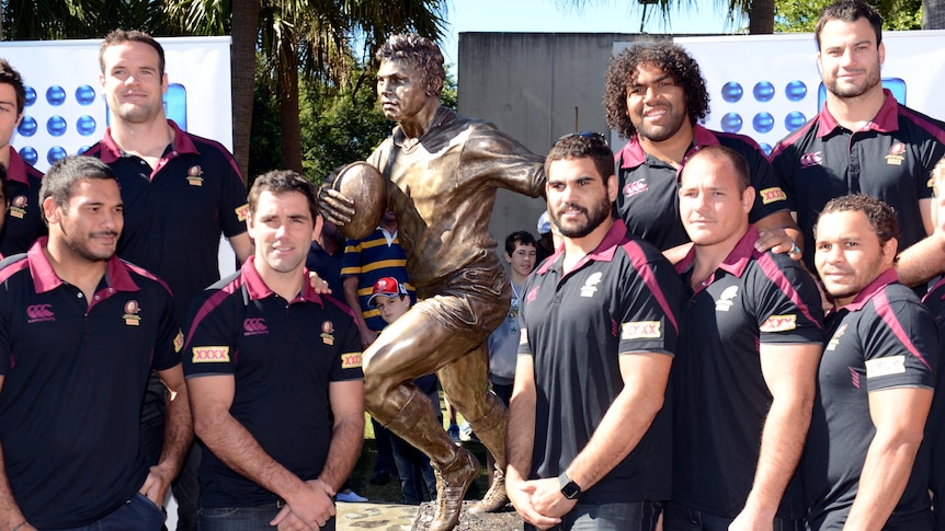 Queensland State of Origin team stand next to the statue of 'Artie' Beetson after it's unveiling.