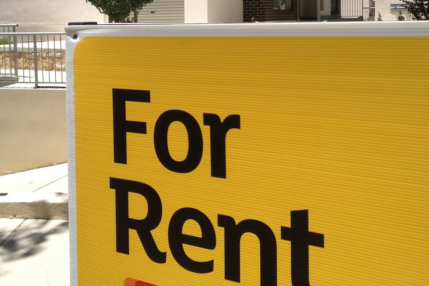Large 'For Rent' sign outside a block of units