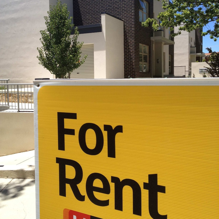 Large 'For Rent' sign outside a block of units