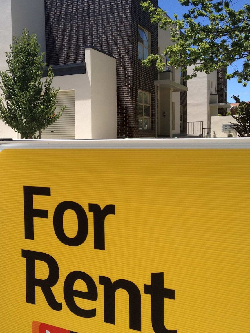 Large 'For Rent' sign outside a block of units