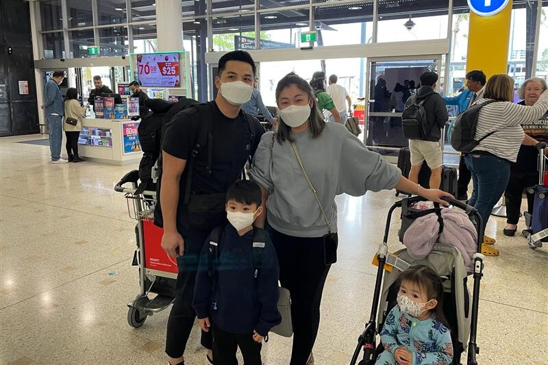 A man and a woman pose for a photo with a boy and a girl inside an airport while wearing face masks.