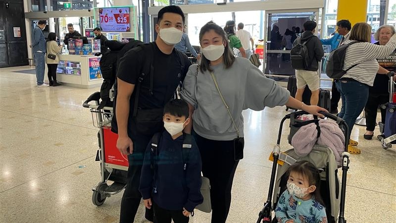 A man and a woman pose for a photo with a boy and a girl inside an airport while wearing face masks.