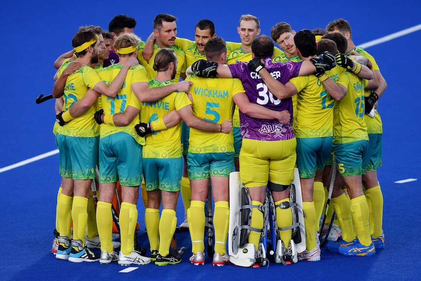 L'équipe australienne de hockey masculin se rassemble en cercle serré, les bras autour des épaules.