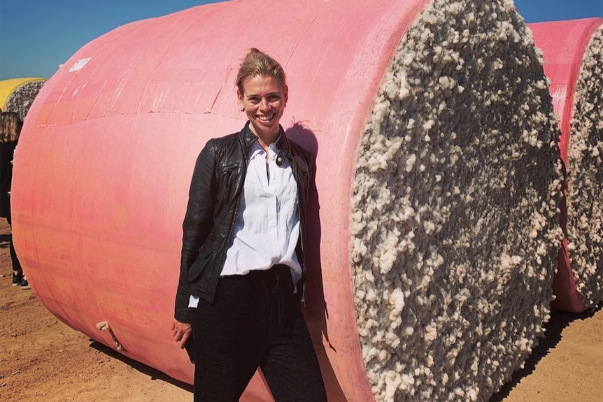 Camille Reed stands in front of a bale of cotton.