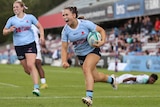 A NSW Waratahs Super W player crosses the goal line to score a try.