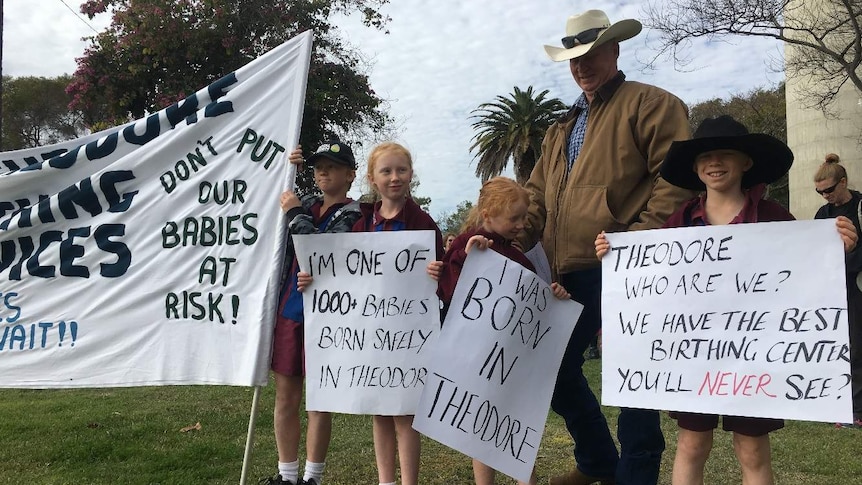 A man stands with four children outside holding protest banners