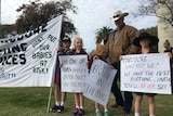 A man stands with four children outside holding protest banners
