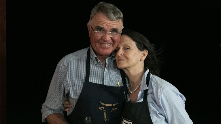 Peter and Jane Hughes stand together smiling wearing Wagyu aprons.