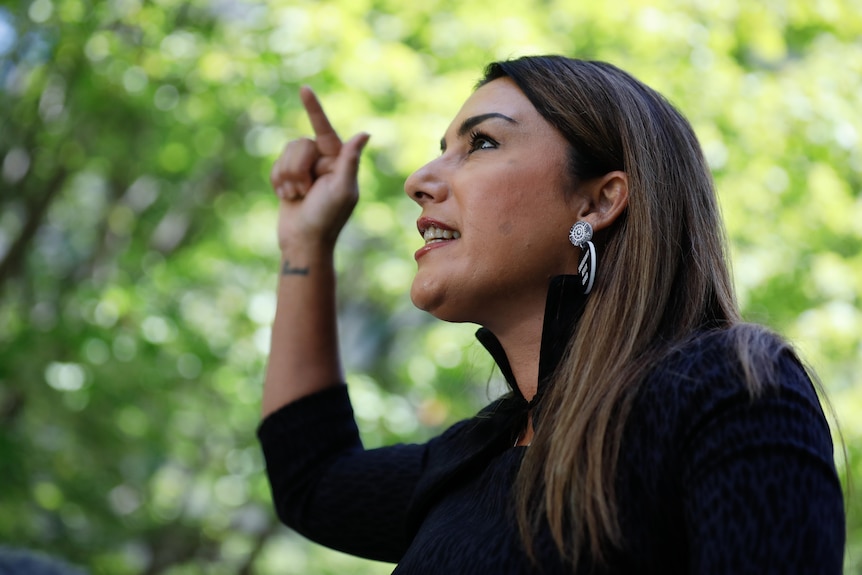 Lidia Thorpe points as she looks up at a press conference 