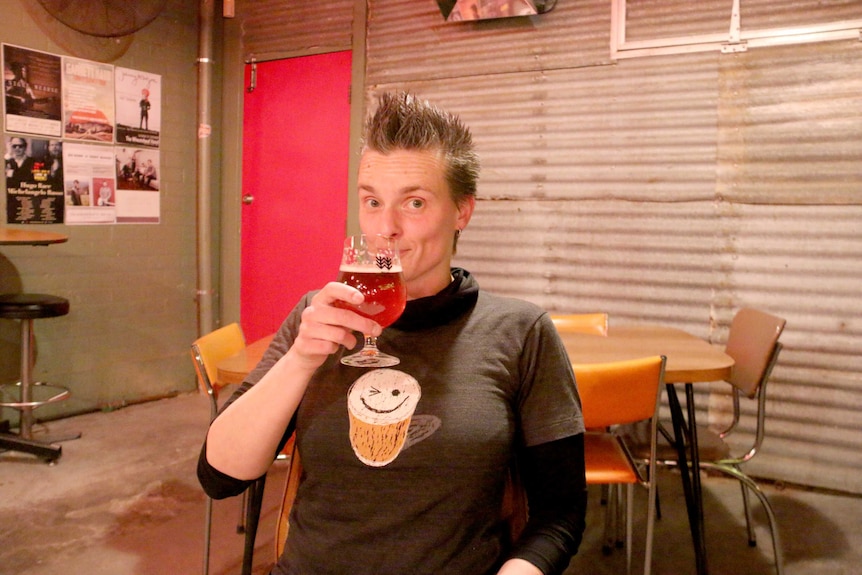 Person drinks a beer at a pub.