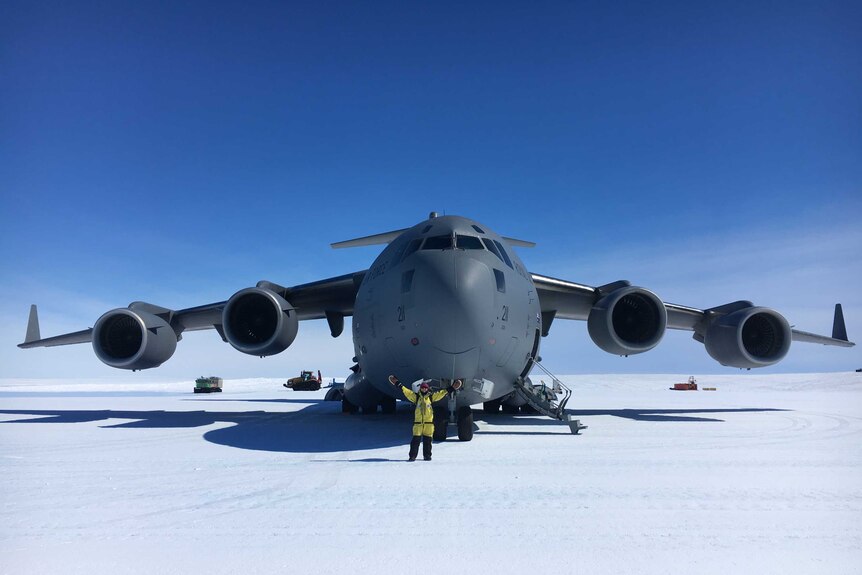 Dianne Jolley stands in front of a large plane on flat ice.