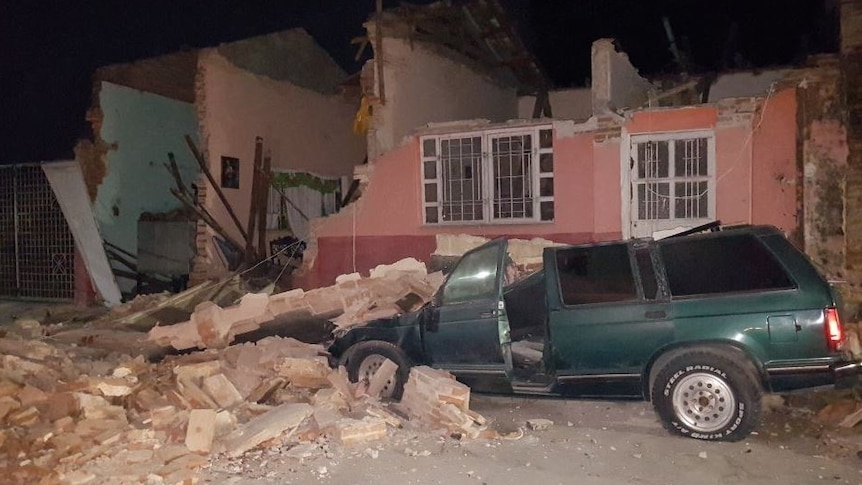 Walls and roofs of buildings are torn off, debris ruins a green station wagon in Chiapas