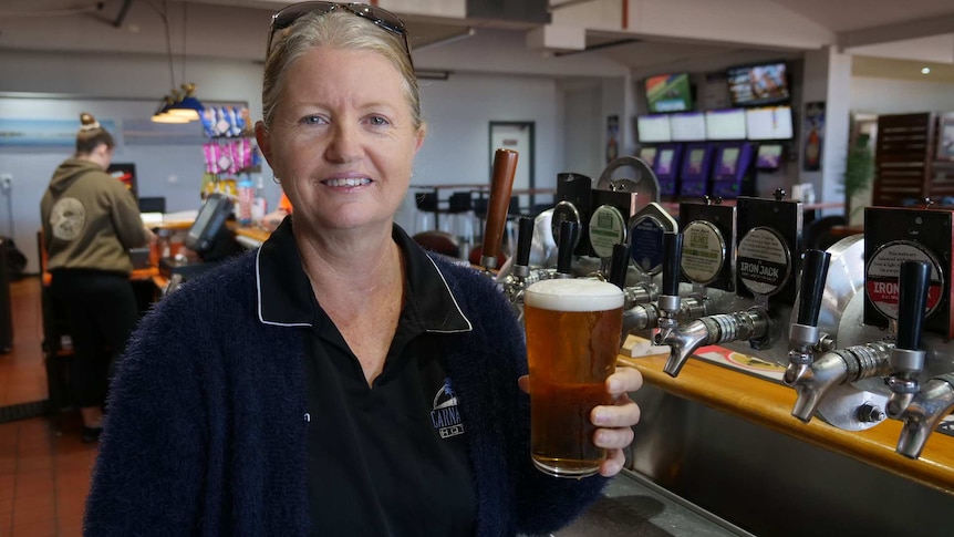 A woman with glasses on her head holding a beer.