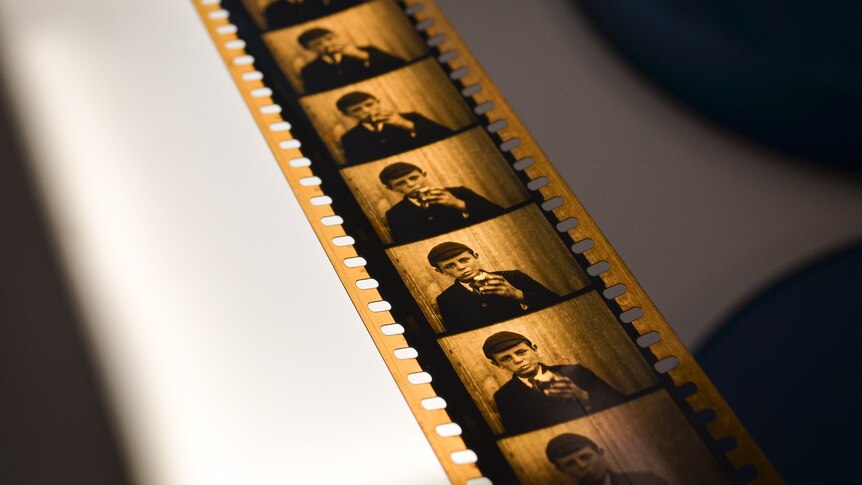 The black and white film is orange in tinge, and shows multiple frame of a boy eating an apple