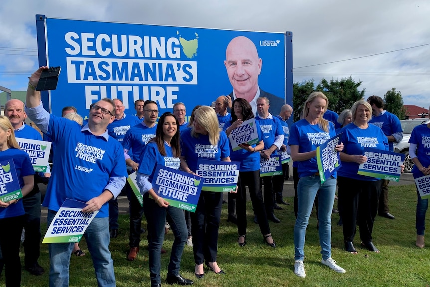 A lot of people clustered together wearing blue Liberal Party t-shirts