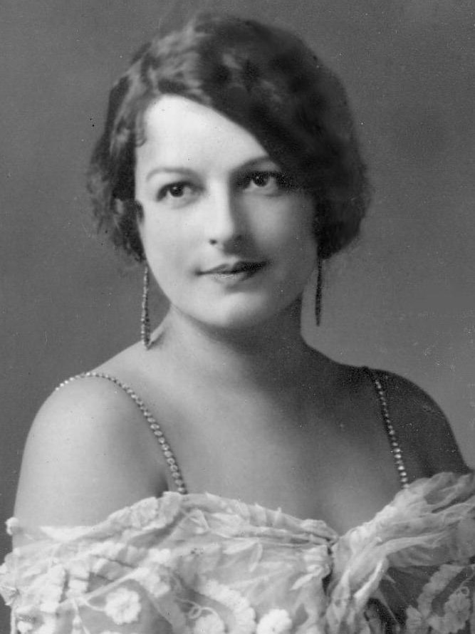A black and white photo of a young attractive woman with short brown hair and a white dress.