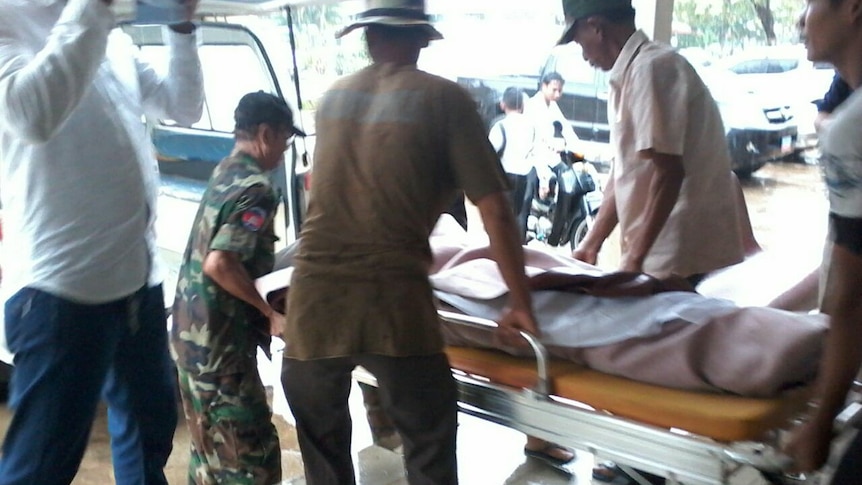 Men carrying a stretcher after an explosion at a shooting range in Cambodia that killed two people, including an Australian man.