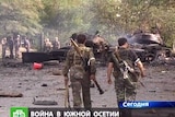 Soldiers walk near a burning tank in Tskhinvali, South Ossetia.