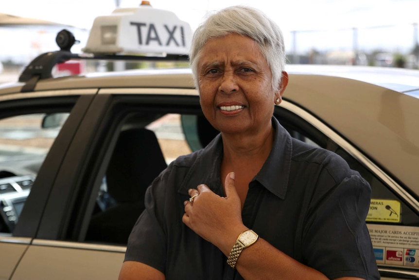 Ms Thomas stands in front of her taxi.