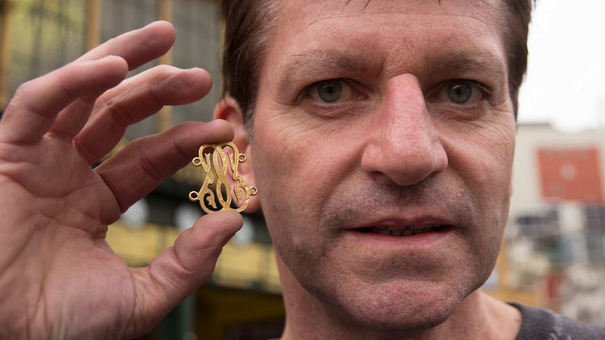 A man holds an intricate gold chain link