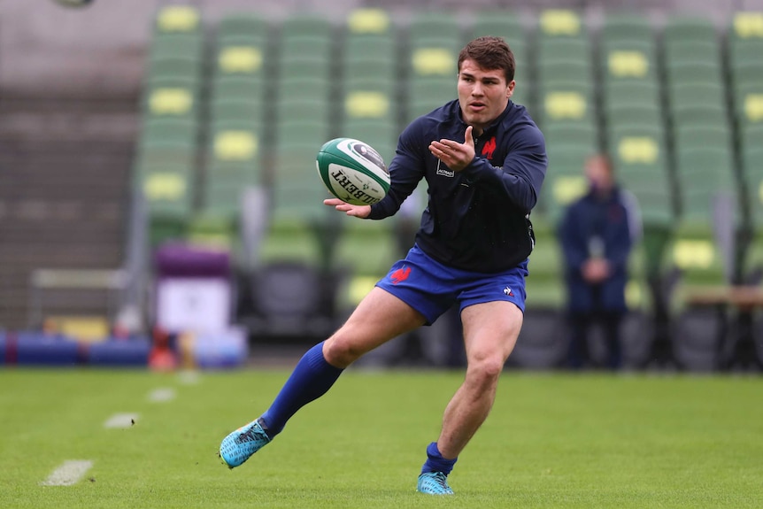 Antoine Dupont throws a pass wearing a dark blue training top