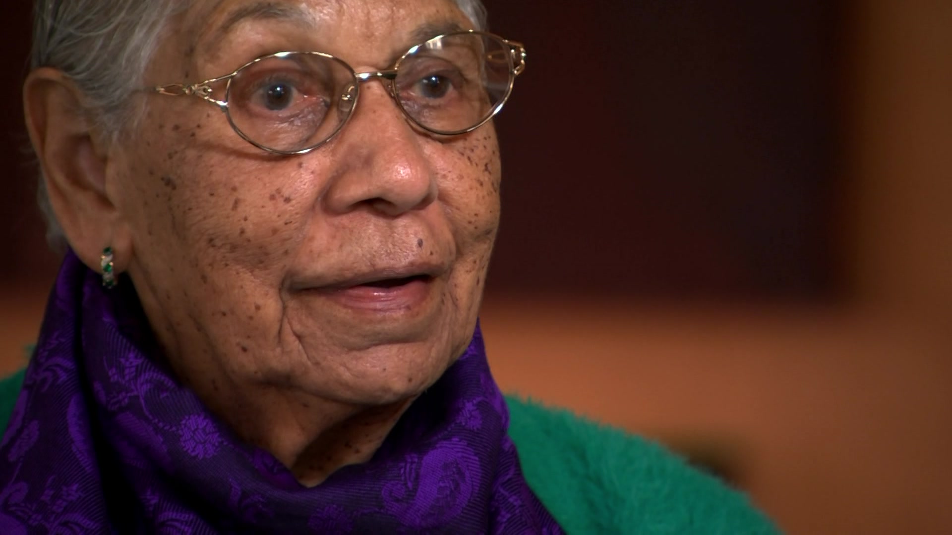a woman in glasses and a purple scarf