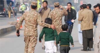 Soldier escorts schoolchildren from the Army Public School