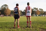 Two junior footballers stand side by side and watch the action during a game.