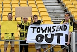 Four Wellington Phoenix fans hold signs protesting about the A-Leagues grand final decision.