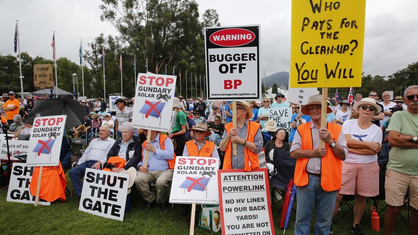 Farmers holding signs at a protest outside Parliament House.