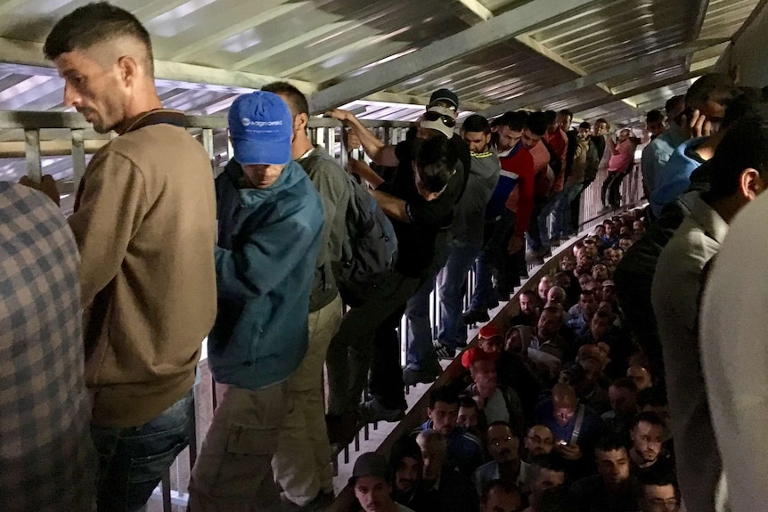 Men climbs the sides of a crammed checkpoint 300 in Bethlehem early in the morning.