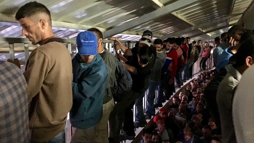 Men climbs the sides of a crammed checkpoint 300 in Bethlehem early in the morning.