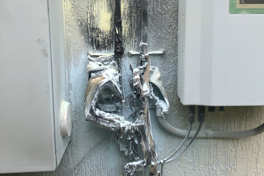 A damaged solar isolator melted after an explosion, with black smoke marking the attached wall