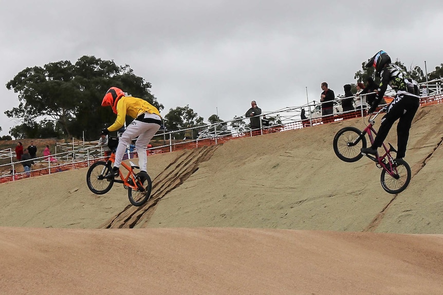 Two BMX riders going over a jump become airborne