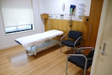 An empty hospital bed and two chairs in a hospital room.