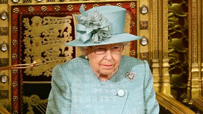 Queen Elizabeth II sitting on her throne in a green costume.