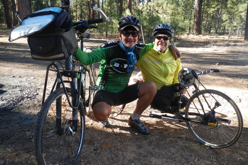 Two men pictured at a camp site with their cycling gear