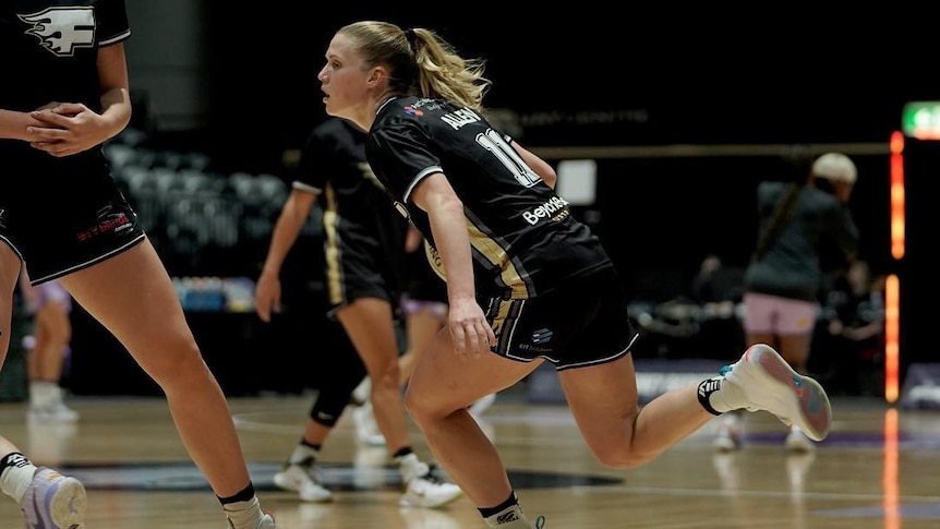 A woman runs low to the ground during a basketball game.