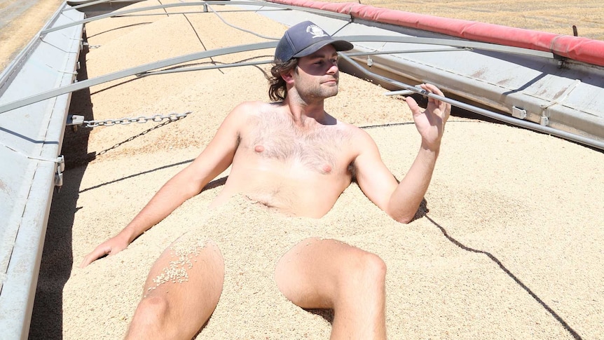 Ben Brooksby wears only a hat and boots in a pile of lentils