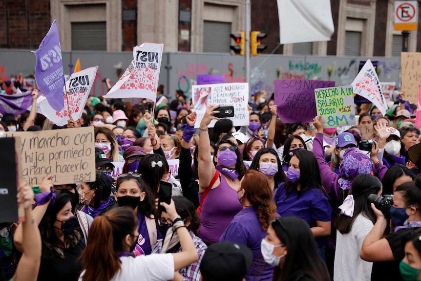 A large group of women in purple clothes holding signs.