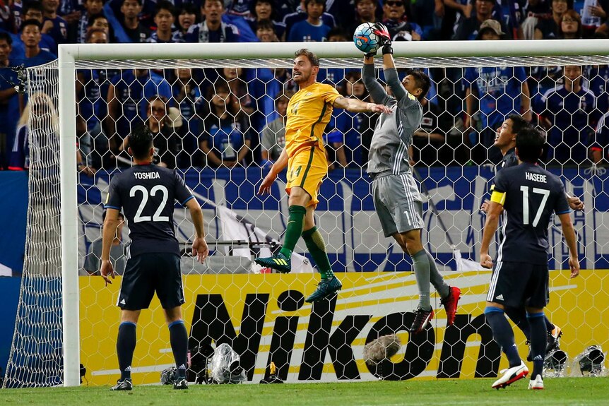 James Troisi rises for a header as Japan's keeper catches the ball.