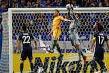 James Troisi rises for a header as Japan's keeper catches the ball.